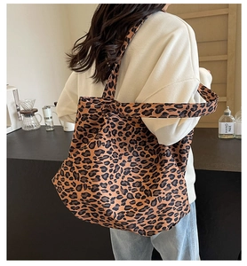 Detail of a large leopard print tote bag worn on shoulder in a warm cafe setting