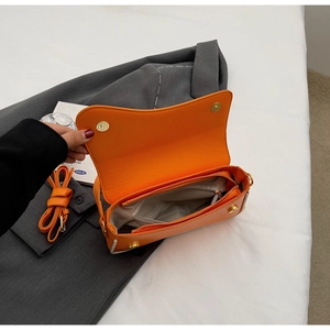 Detail van de oranje PU-schoudertas met binnenvakken en magnetische sluitingen