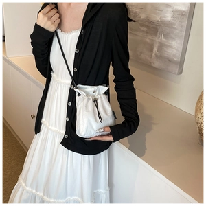 Detail of white nylon mini bucket bag with silver eyelets and black drawstring