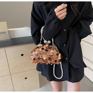 Detailed macro of a rose gold sequin clutch bag with luxury pearl handle and chain