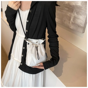 Mini nylon drawstring crossbody bag shown on model highlighting compact size and texture