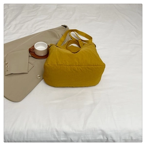 Détail d'un grand sac fourre-tout jaune en nylon plissé avec une large bandoulière