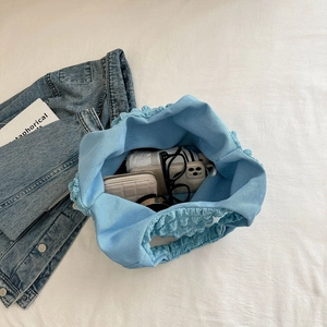 Himmelblaue Tasche mit Faltenstruktur zeigt Stauraum für Regenschirm und Handy