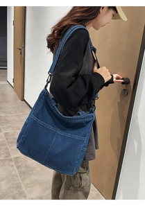 Dettaglio borsa a tracolla in denim blu con grandi tasche frontali e cuciture a contrasto