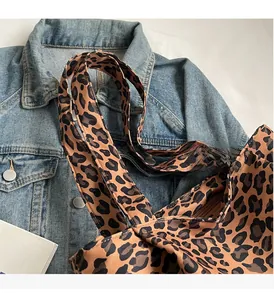 Detail of leopard print tote bag with sturdy handles and zipper on denim jacket