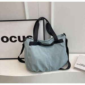 Detailed side view of the spacious light blue canvas tote bag on a white surface