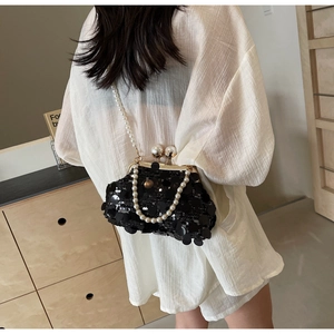 Detail view of black sequined bag with pearl shoulder strap and large pearl closure clasp
