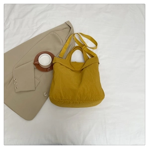 Détail du sac fourre-tout jaune moutarde en nylon montrant la texture douce et la bandoulière