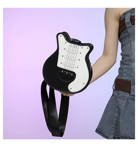 Detail shot of a black and white guitar-shaped crossbody bag featuring silver rivet accents