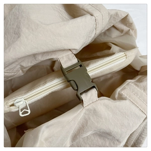Détail du sac en nylon crème avec boucle verte et texture de tissu froissé durable