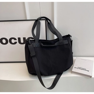 Detailed view of black canvas tote bag showing wide straps and durable material for daily use