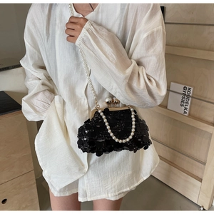 Detail of a black sequin evening bag with gold kiss lock and white pearl chain strap