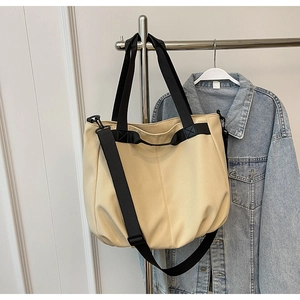 Detail of canvas tote bag with black straps hanging next to a classic denim jacket
