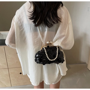 Detail of black sequin evening bag featuring pearl strap and golden metal clip clasp