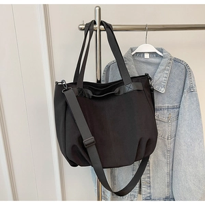 Detail of a black canvas tote bag with adjustable shoulder strap and sturdy handles