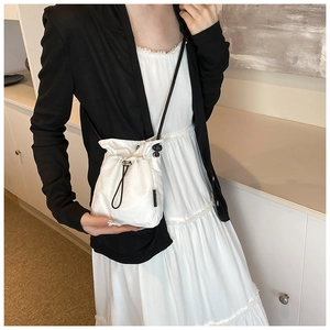 Detail of white mini nylon drawstring bucket bag with black strap and brand woven label