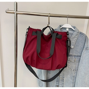 Detail of burgundy large capacity canvas tote bag with black straps and adjustable shoulder belt