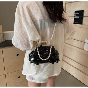 Close-up of black sequin evening bag with gold metal clasp and pearl chain straps