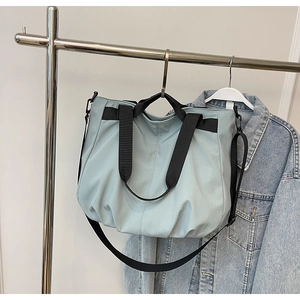Detail of light blue large capacity tote bag with black straps and adjustable shoulder strap
