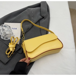Detail van gele baguette tas met bruine rand en een verstelbare lange schouderriem