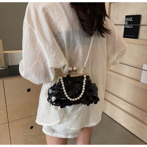 Detail of black sequined crossbody bag featuring pearl strap and metal clasp closure