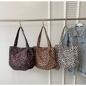 Detailed display of three leopard print tote bags in brown and black on display hooks