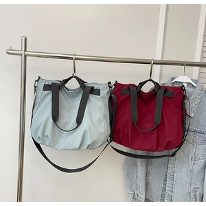 Detail view of light blue and burgundy pleated tote bags with adjustable straps