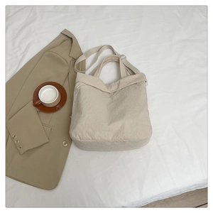 Vue détaillée d'un grand sac cabas beige avec texture naturelle sur un fond de literie blanc