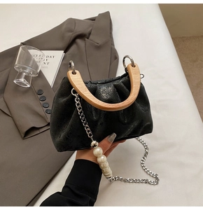 Détail du sac seau plissé noir avec poignée en bois et bandoulière perles et chaîne