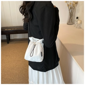 Detailed back view of a white nylon drawstring bucket bag on a model in a minimalist room