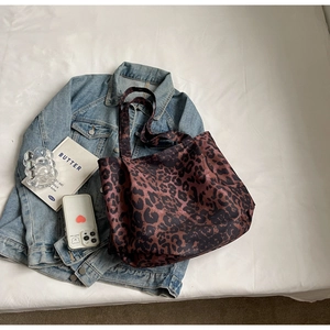 Flat lay of a large leopard print canvas tote bag with denim jacket and accessories