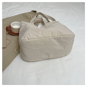 Gros plan d'un sac cabas beige avec texture plissée et large bandoulière souple