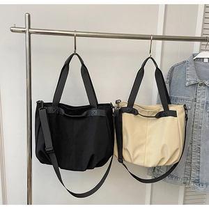 Detail of canvas tote bags in black and beige hanging on rack with adjustable straps