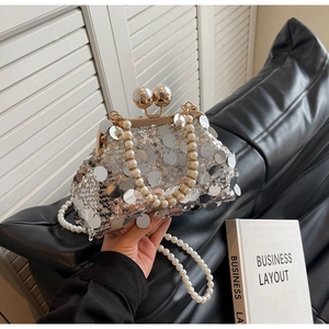 Detail of silver sequined evening clutch bag with pearl handle and golden snap closure