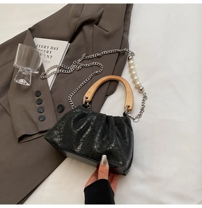 Détail du sac plissé avec poignée en bois et chaîne en argent ornée de perles