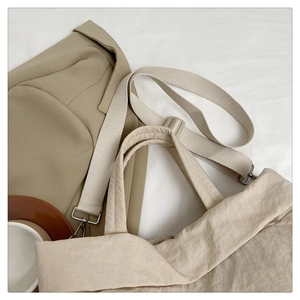 Détail d'un sac cabas beige à grande capacité avec des crochets métalliques argentés