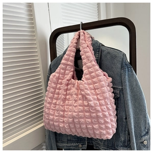 Pink bubble textured handbag showing cloud-like fabric detail against a denim jacket