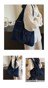 Detail of denim tote bag showing orange circular stitching and front flap pockets