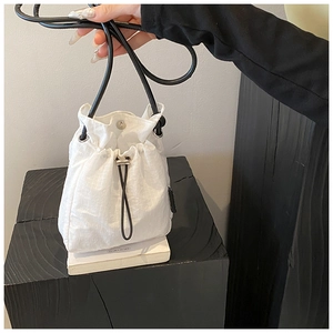 Detail of white nylon drawstring bucket bag with textured grid pattern and slim strap
