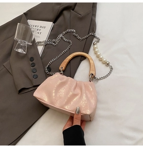 Détail du sac nuage plissé rose clair avec poignée en bois, chaîne argentée et perles