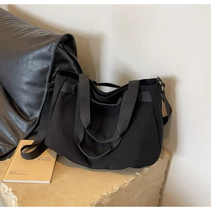 Detail of black canvas tote bag showing adjustable strap and premium metal hardware