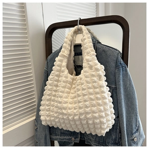 Macro detail of creamy white bubble textured fabric on a stylish shoulder tote bag