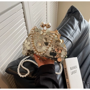 Close-up of golden sequin evening clutch with pearl handle and metal ball clasp