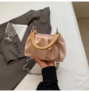Détail du sac seau plissé rose avec poignée en bois et chaîne de perles