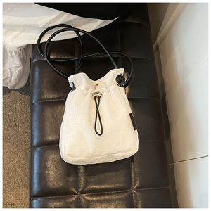 Detail of white nylon mini bucket bag featuring mesh texture and drawstring closure