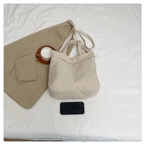 Détail du sac cabas beige en nylon à texture froissée sur un drap blanc épuré
