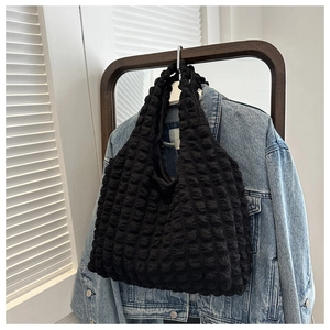 Detail of black textured bubble fabric on a stylish casual shoulder bag against denim