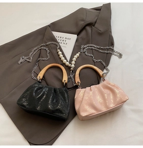 Détail du sac seau plissé avec poignée en bois, finition pailletée dorée et chaîne de perles