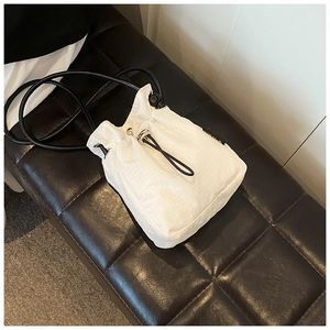 Detail of white grid texture nylon bucket bag with black drawstring closure and silver buckle