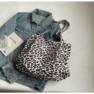 Flat lay of a large leopard print tote bag with a denim jacket and props for styling